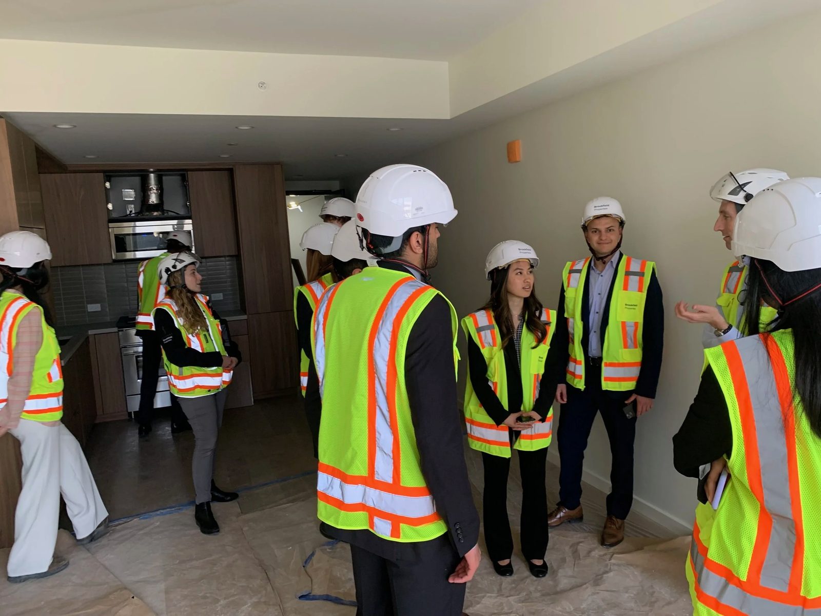 Members in hard hats and safety vests inside an apartment under construction.